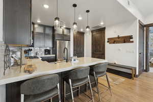 Kitchen with a breakfast bar, a peninsula, glass insert cabinets, hanging light fixtures, and backsplash