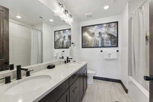Bathroom with double vanity, recessed lighting, and shower / tub combo with curtain
