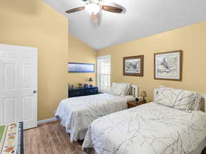 Bedroom featuring vaulted ceiling, wood finished floors, and a ceiling fan