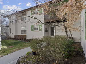 View of property exterior with a balcony, stucco siding, and a yard