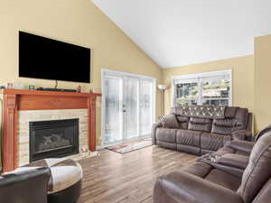 Living area featuring wood finished floors, high vaulted ceiling, and a fireplace