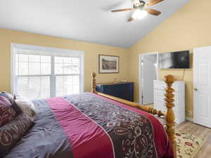 Bedroom featuring vaulted ceiling, wood finished floors, and a ceiling fan