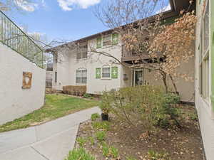 Exterior space featuring stucco siding, a front yard, and a balcony