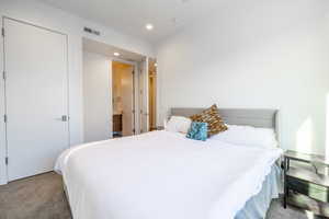 Carpeted bedroom with ensuite bathroom and recessed lighting