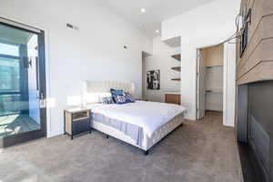 Bedroom featuring carpet floors, a walk in closet, recessed lighting, access to exterior, and a high ceiling