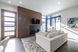 Living area with a large fireplace, wood-type flooring, and recessed lighting