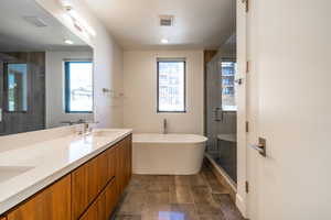 Bathroom featuring double vanity, a freestanding bath, a stall shower, and recessed lighting