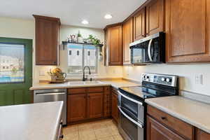Kitchen featuring appliances with stainless steel finishes, brown cabinets, healthy amount of natural light, and recessed lighting