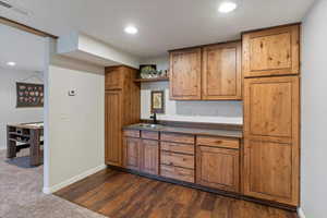 Kitchen featuring dark wood-style floors, recessed lighting, brown cabinetry, open shelves, and dark countertops