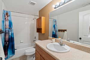 Bathroom with shower / bath combo with shower curtain, vanity, a textured ceiling, and light tile patterned flooring