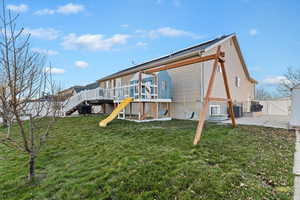 Back of house featuring a wooden deck, a playground, a gate, and stairway