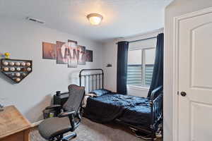 Carpeted bedroom with a textured ceiling