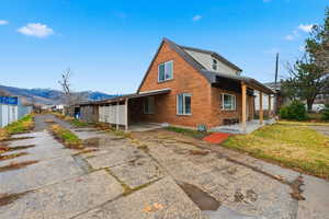 Rear view of property featuring brick siding, a porch, and a mountain view