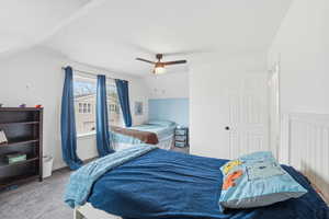 Carpeted bedroom featuring ceiling fan and lofted ceiling