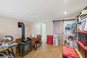 Interior space featuring light wood finished floors, washer / clothes dryer, a barn door, and a wood stove