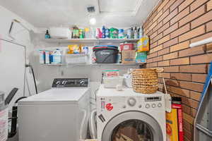 Laundry room with brick wall and independent washer and dryer
