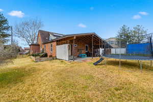 Rear view of house with a patio, brick siding, and a trampoline