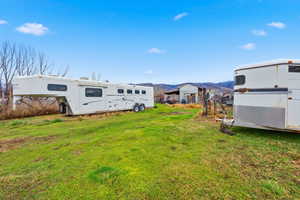 View of green lawn featuring an outbuilding and a mountain view