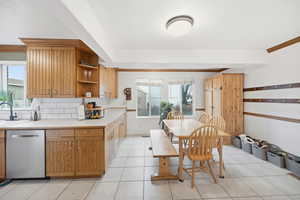 Kitchen featuring brown cabinets, light countertops, dishwasher, crown molding, and open shelves
