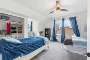 Carpeted bedroom featuring ceiling fan and lofted ceiling