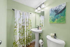 Full bathroom with a shower with shower curtain, a textured ceiling, and wood finished floors