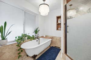 Full bathroom with a soaking tub, a stall shower, a chandelier, and tile walls