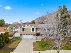 Split foyer home featuring a mountain view, driveway, a garage, and a front lawn