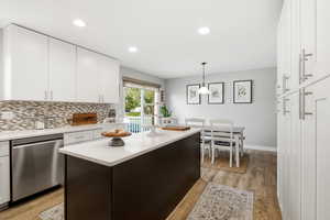 Kitchen with dishwasher, white cabinetry, decorative light fixtures, a center island, and tasteful backsplash