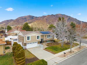 View of front of house with concrete driveway, a mountain view, an attached garage, and solar panels
