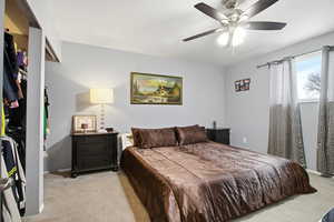 Carpeted bedroom with ceiling fan and baseboards