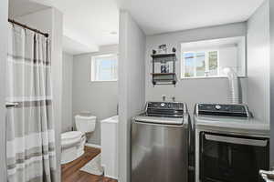 Washroom with washer and clothes dryer, dark wood finished floors, and plenty of natural light