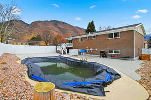 View of swimming pool featuring a patio area, a fenced backyard, stairs, a mountain view, and grilling area