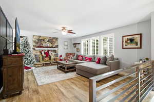 Living area featuring light wood finished floors, a ceiling fan, and a fireplace