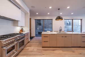 Kitchen featuring modern cabinets, double oven range, exhaust hood, light stone counters, and recessed lighting
