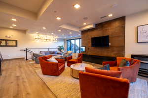 Living area featuring light wood finished floors, a raised ceiling, and recessed lighting