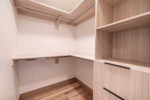 Walk in closet with light wood finished floors