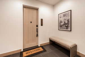 Foyer entrance featuring dark tile patterned flooring and baseboards