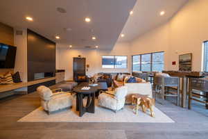 Living room featuring elevator, wood finished floors, recessed lighting, and a high ceiling