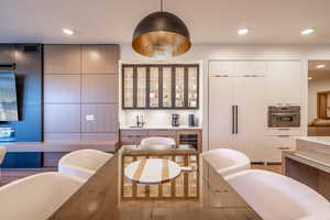 Kitchen with modern cabinets, oven, paneled fridge, recessed lighting, and glass insert cabinets
