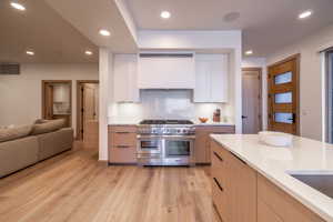 Kitchen with modern cabinets, recessed lighting, double oven range, white cabinetry, and range hood