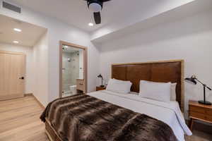 Bedroom with light wood-style floors, recessed lighting, ensuite bath, and ceiling fan