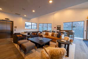 Living room with elevator, wood finished floors, recessed lighting, and high vaulted ceiling