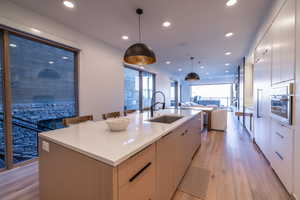 Kitchen with modern cabinets, recessed lighting, a large island, pendant lighting, and light wood finished floors