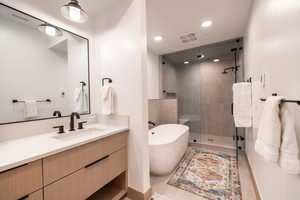 Bathroom with a freestanding bath, a stall shower, vanity, and recessed lighting