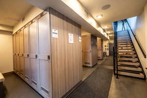 Corridor featuring finished concrete flooring, stairs, and elevator