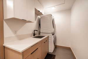 Laundry room featuring stacked washer / drying machine and cabinet space
