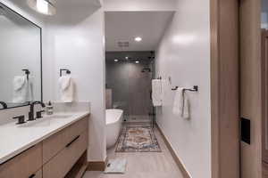 Bathroom featuring a shower stall, vanity, a freestanding tub, and recessed lighting