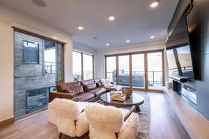 Living area featuring wood-type flooring, recessed lighting, and a glass covered fireplace