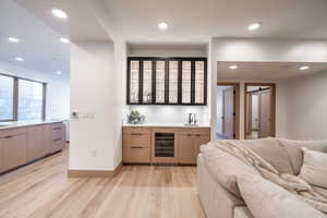 Indoor wet bar featuring glass insert cabinets, light wood-style floors, wine cooler, modern cabinets, and recessed lighting