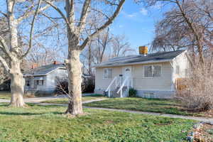 Bungalow featuring a chimney and a front lawn